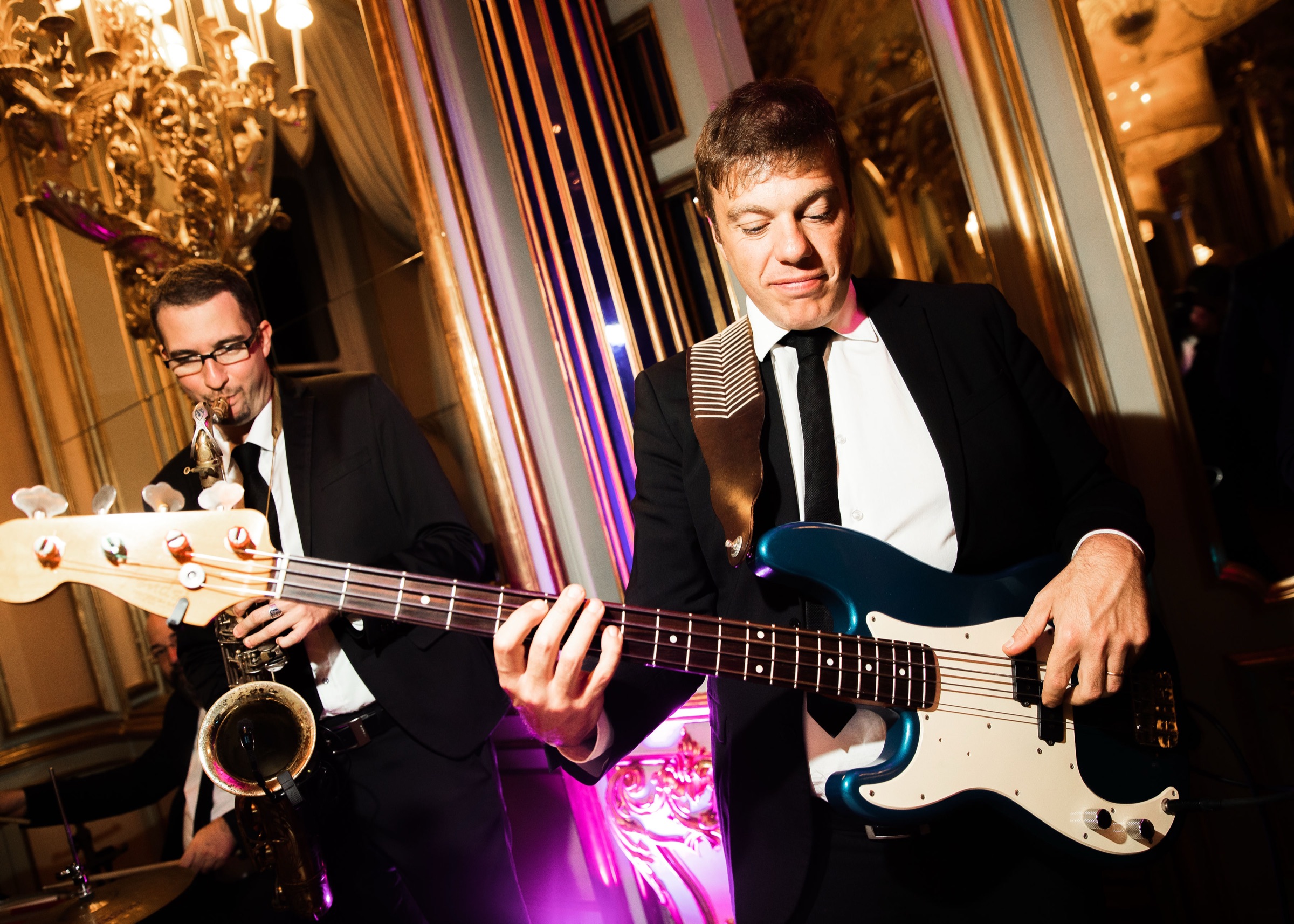 Saxophonist and bass guitarist of the Italian Jazz Band playing in a gilded ballroom at a wedding in Italy
