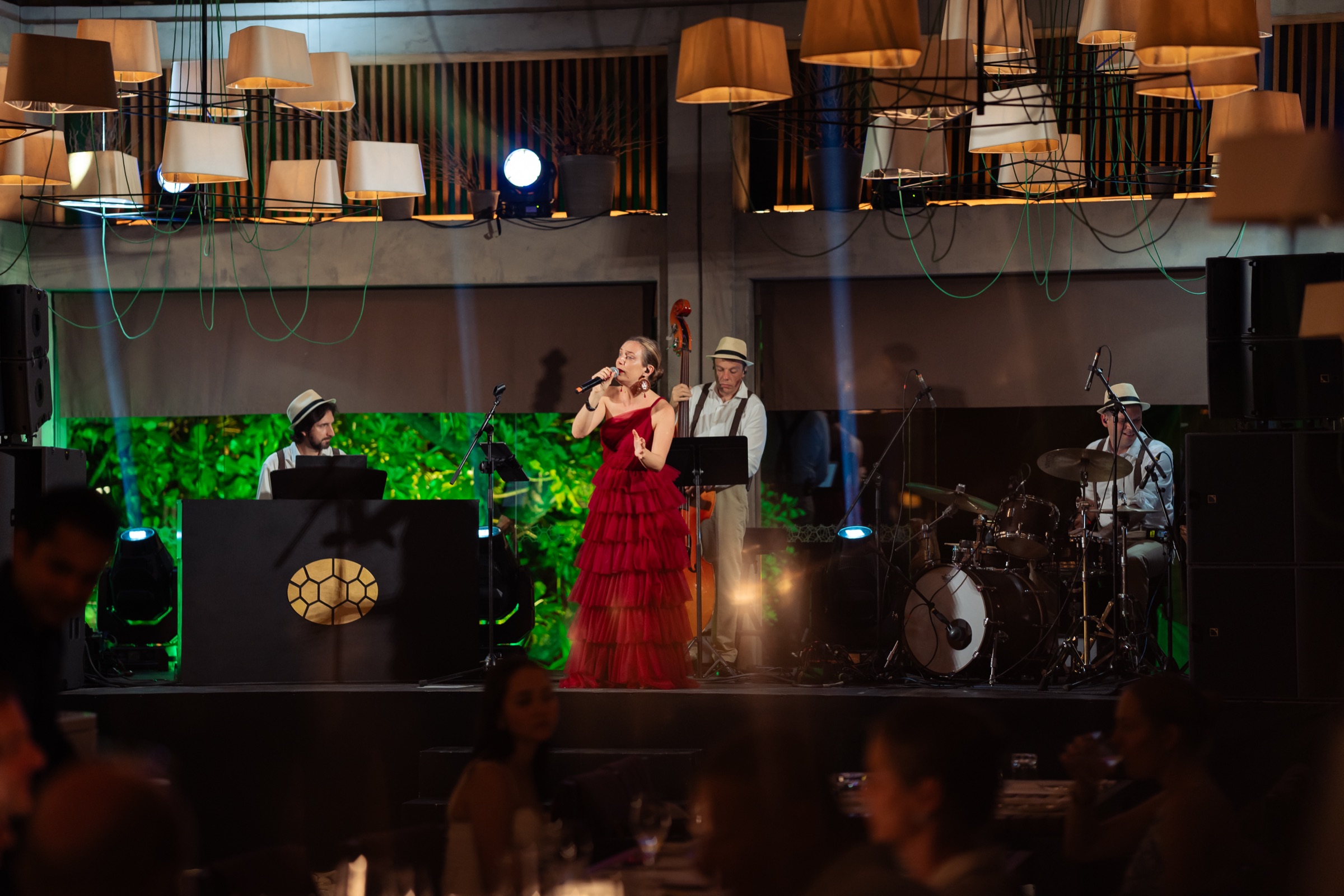 Vocalist in a red tiered gown on stage with lamps and hats at an event on a private island in the Maldives